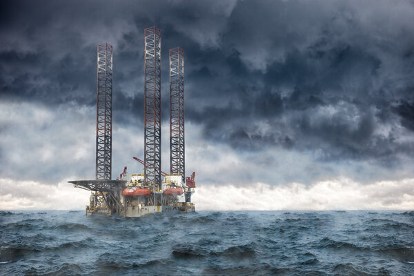 An oil rig in the ocean during strong waves and dark clouds