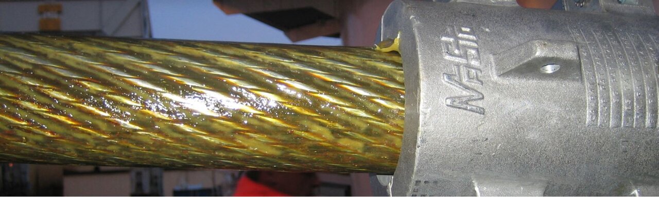 Masto Lubricator of steel wire rope A close up of the lubricator and steel wire rope with lubrication on it