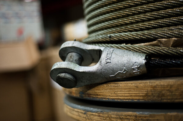 A close up of a steel wire rope with a socket on a wooden reel for use on a crane