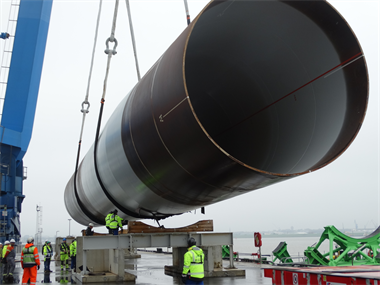 A wind turbine tower being lifted with lifting slings and a spreader beam