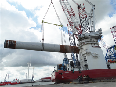 A Wind Turbine Tower being lifting to a vessel